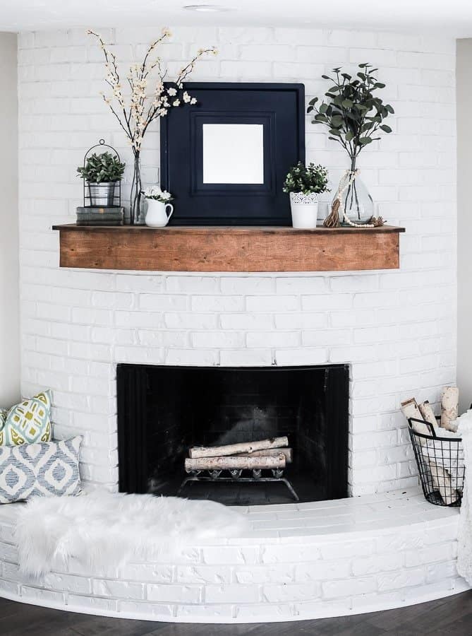This modern farmhouse mantel idea is keeping it trendy and simple by adding in darker colors, such as navy blue, on the centerpiece and choosing to keep the rest natural tones. 